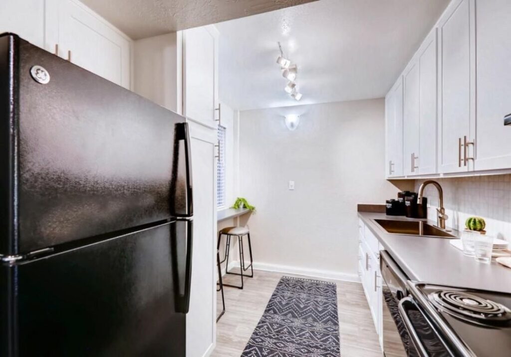 Apartment kitchen with bar seating, cabinets, and appliances