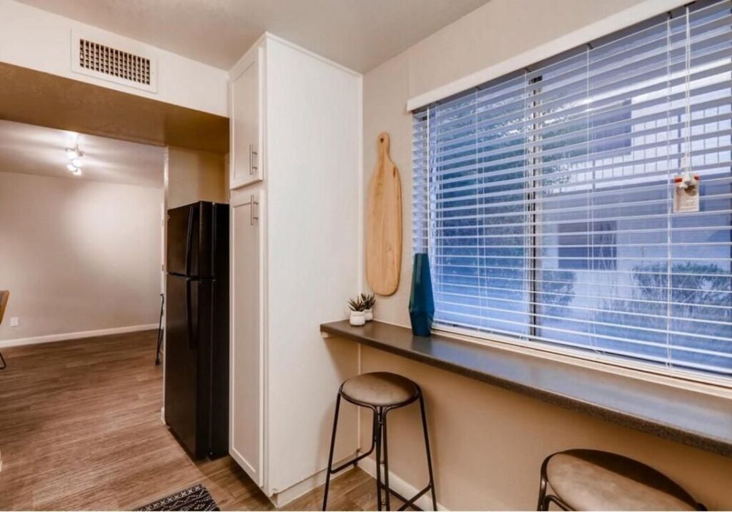 Apartment kitchen with cabinets, bar seating, and black appliances