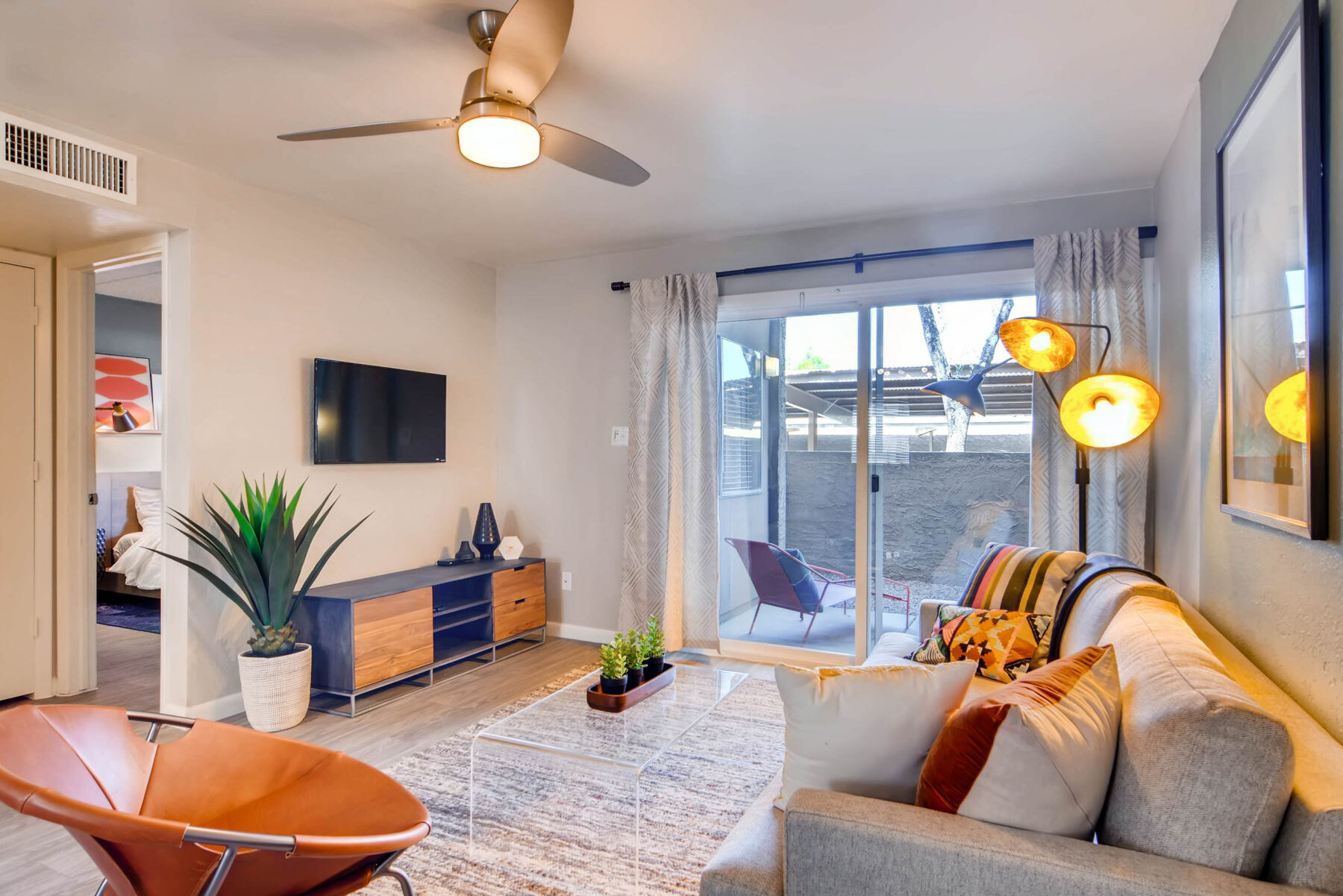 Apartment living room with wood-style flooring, ceiling fan, and sliding door leading to outdoor patio