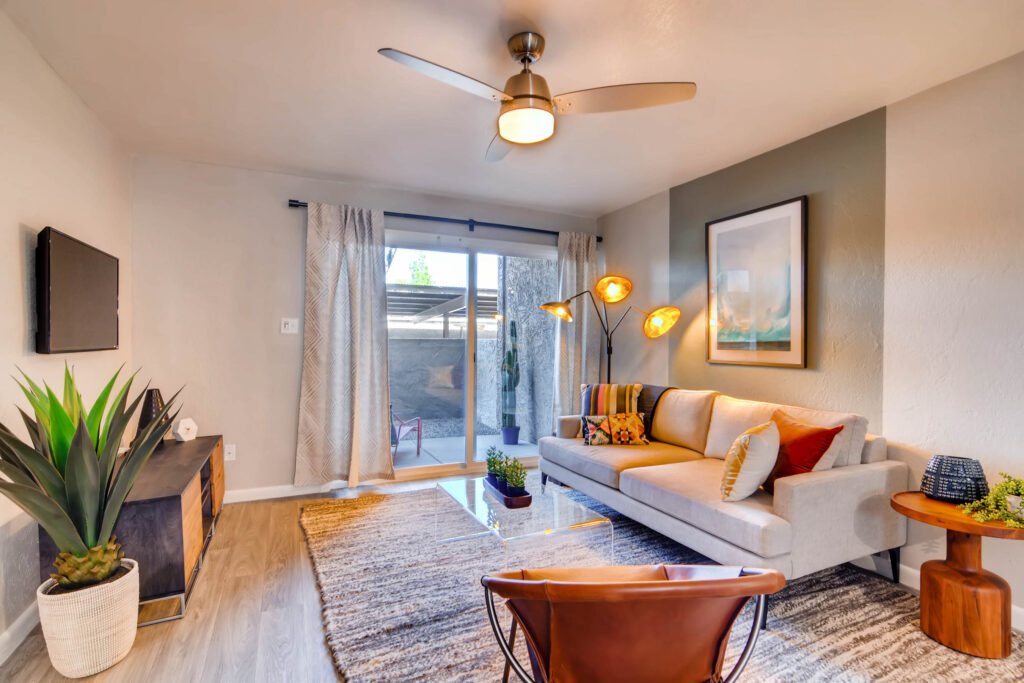 Apartment living room with wood-style flooring, ceiling fan, and sliding door leading to outdoor patio