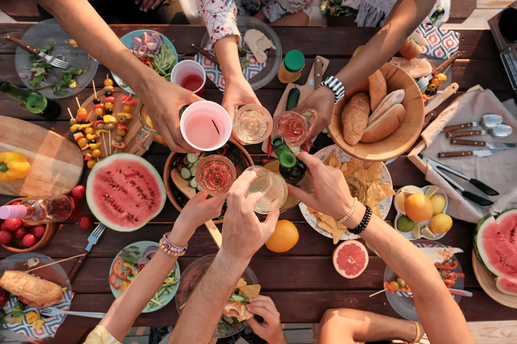 Table of food with group of people holding up their drinks in celebration